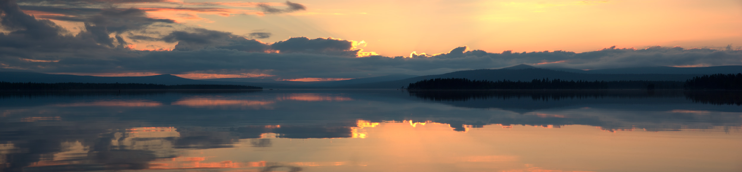 Panorama med midnattssol över sjö i fjällen